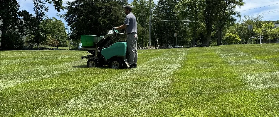 Tech on a granular spreader treating a lawn in Westminster, MD.