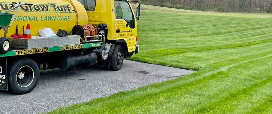 Yellow company truck beside a lush, green lawn in Westminster, MD.