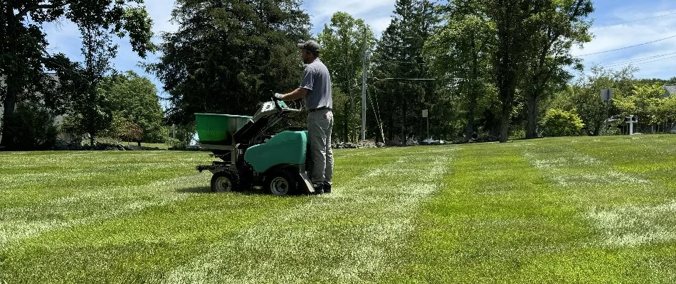 Lawn in Randallstown, MD, with a man on a fertilizer spreader machine.